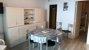 A dining area with a round table, four chairs, and a buffet cabinet with shelves.