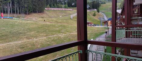 A balcony with a view of a mountainous landscape, a ski lift, and a small building.