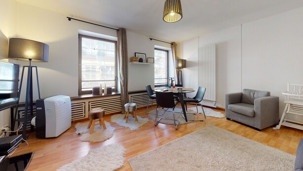 Una sala de estar moderna con un sofá, una mesa de comedor con sillas, un televisor y un radiador.
