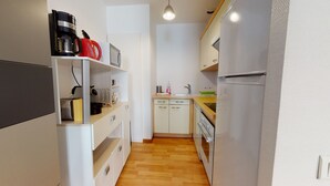Cocina compacta con refrigerador, estufa, microondas y cafetera.