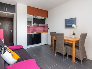 A compact living space with a kitchenette, a dining area with wicker chairs, and a sofa with a yellow bag. - Beachside Studio with Dune Views, Seignosse - Renovated, Prime Location! (Seignosse)