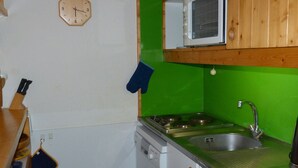 Cocina compacta con microondas, fregadero y estufa.