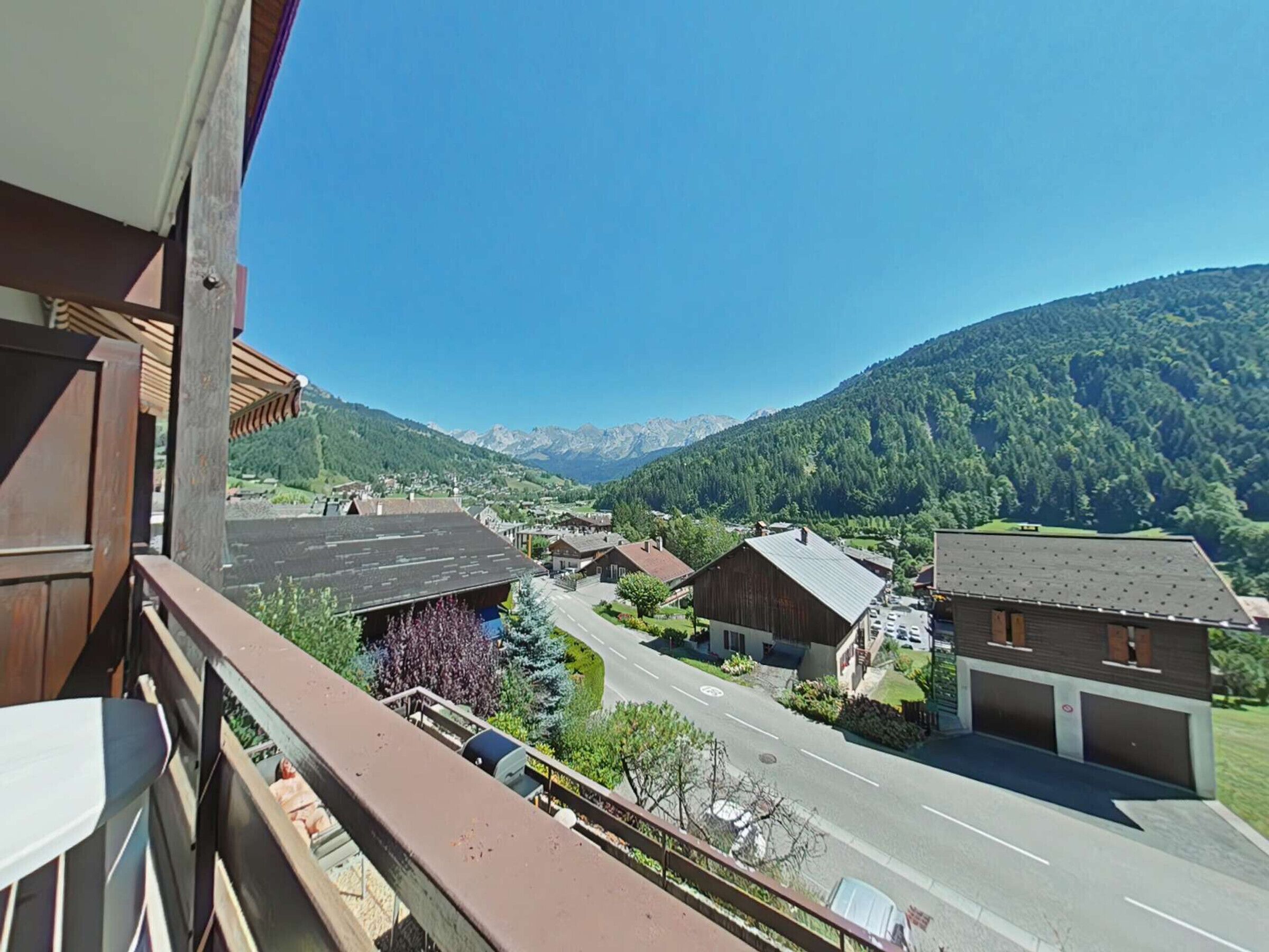 Ein Balkon mit Blick auf eine kleine Stadt, eine Straße und ein Gebirge.