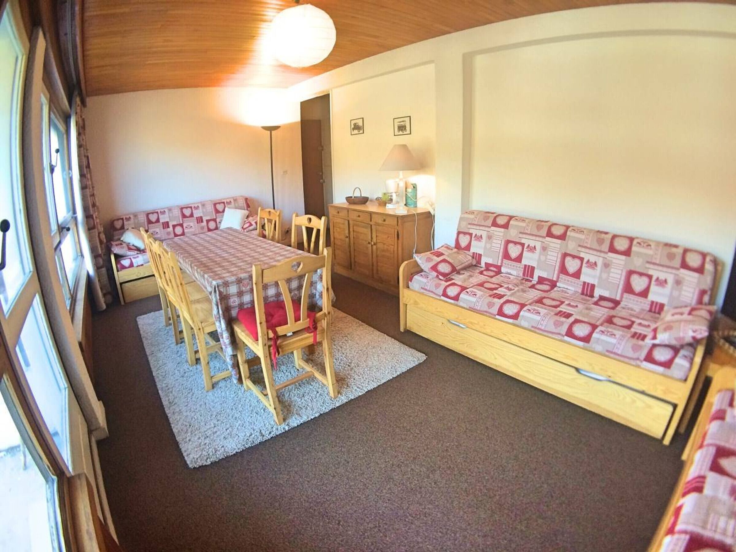 Une pièce chaleureuse avec une table à manger en bois, des chaises, un canapé et un buffet.