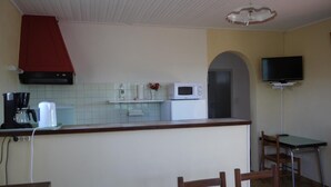 A kitchen with a microwave, coffee maker, and a red hood. There is a TV mounted on the wall and a small table with chairs. - Gîte au milieu des Vignes G286 (Vidauban)