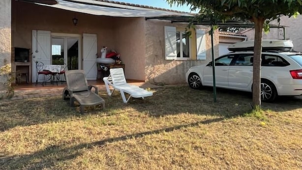 A covered outdoor area with a car parked nearby, a tree, and a building with a door and windows. - Gîte au milieu des Vignes G286 (Vidauban)
