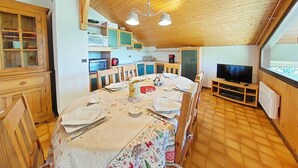 Ein gemütliches Holzinnenambiente mit Essbereich, Küche und Fernseher.