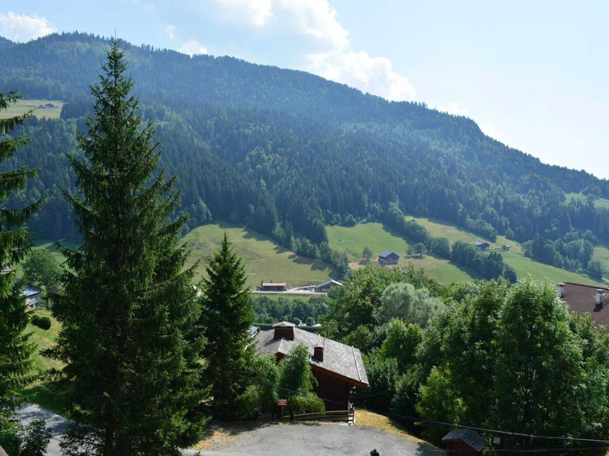 Ländliche Landschaft mit einem Berg im Hintergrund, blauem Himmel und einigen Gebäuden mit traditioneller Architektur.