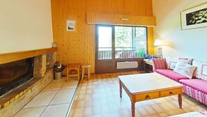 Ein gemütliches Wohnzimmer mit Kamin, Holzböden, einer Couch und einem Tisch.