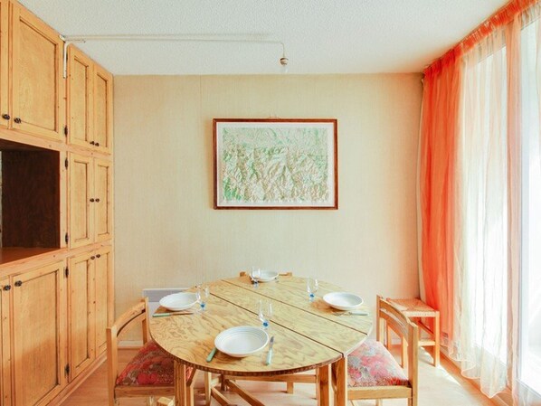 A dining room with a round wooden table, chairs, and a painting on the wall. - Cauterets Studio 4p avec Balcon, Centre-Ville, Proche Télécabine, Ski et Activités Familiales (Cauterets)