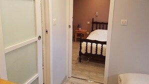 A bedroom with a bed, a nightstand, and a door leading to another room.