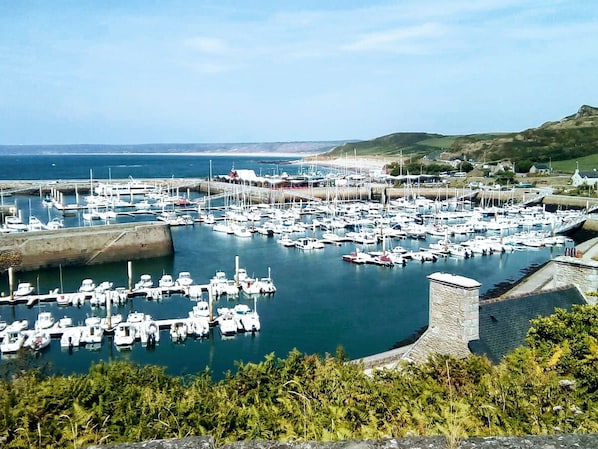 A marina with numerous boats docked, surrounded by greenery and hills. - Charming house with fireplace and private garden (Surtainville)