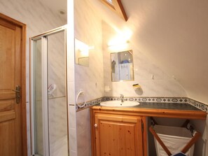 A bathroom with a wooden vanity, a sink, and a mirror. - Charming house with fireplace and private garden (Surtainville)