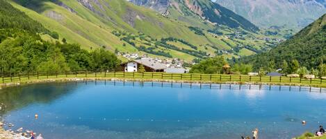 Ein ruhiger See, umgeben von üppigen grünen Hügeln und Bergen.