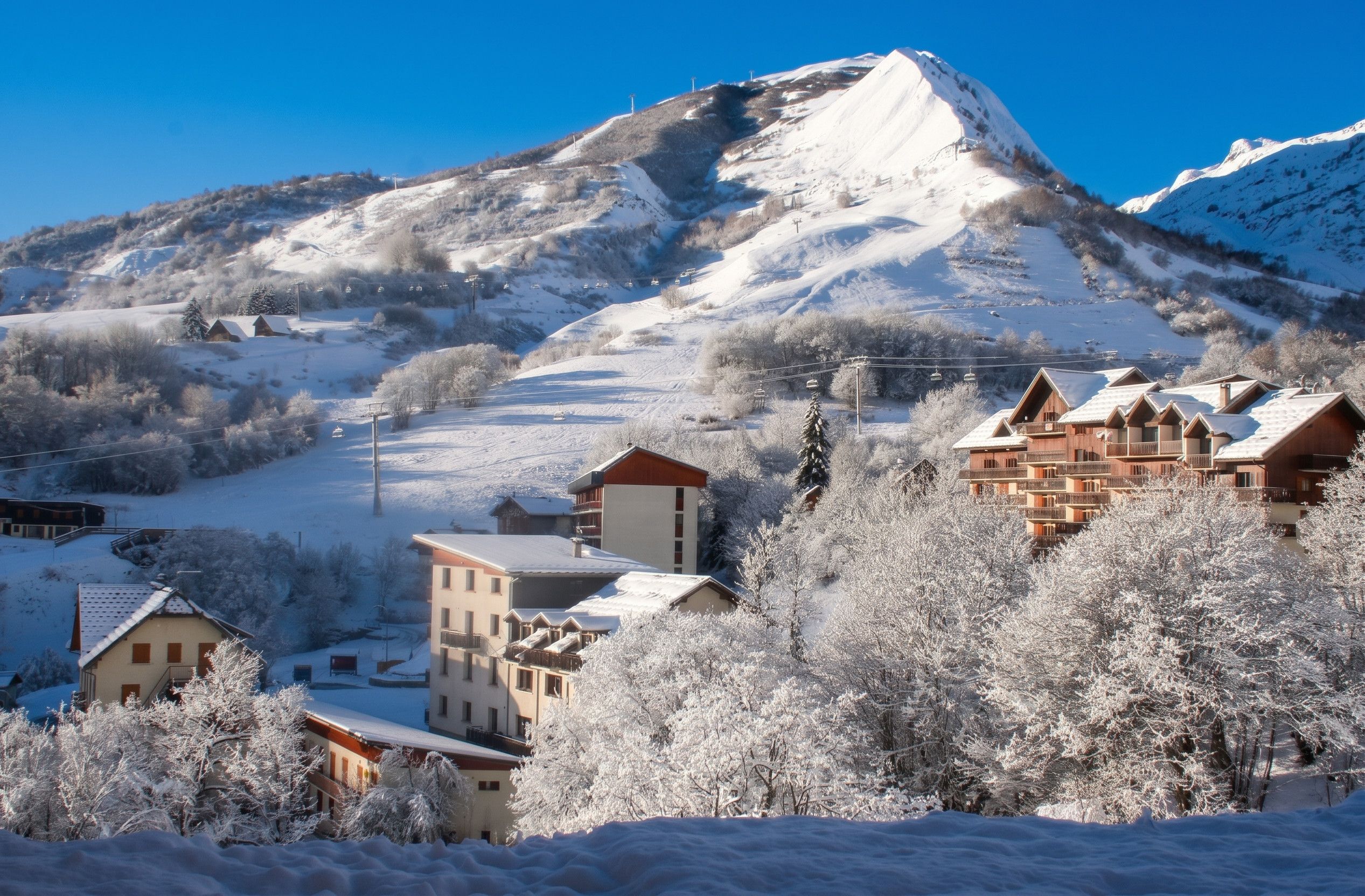 A mountain resort with snow-covered buildings and a ski lift.