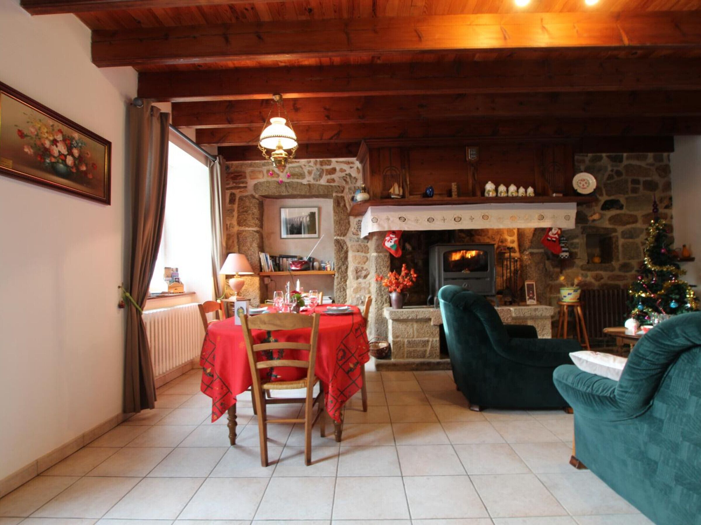 A cozy living room with a stone fireplace, a dining area with a table and chairs, and a green sofa.
