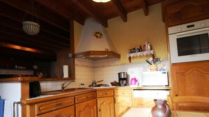 Une cuisine avec des meubles en bois, une cuisinière, un évier et un dosseret carrelé.