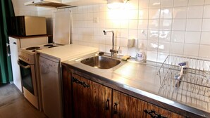 Une cuisine avec des murs carrelés de carreaux blancs, des appareils électroménagers en acier inoxydable, des meubles de rangement en bois et un égouttoir à vaisselle.