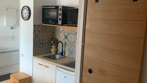 Cuina petita amb microones, rentapelats i armaris blancs.