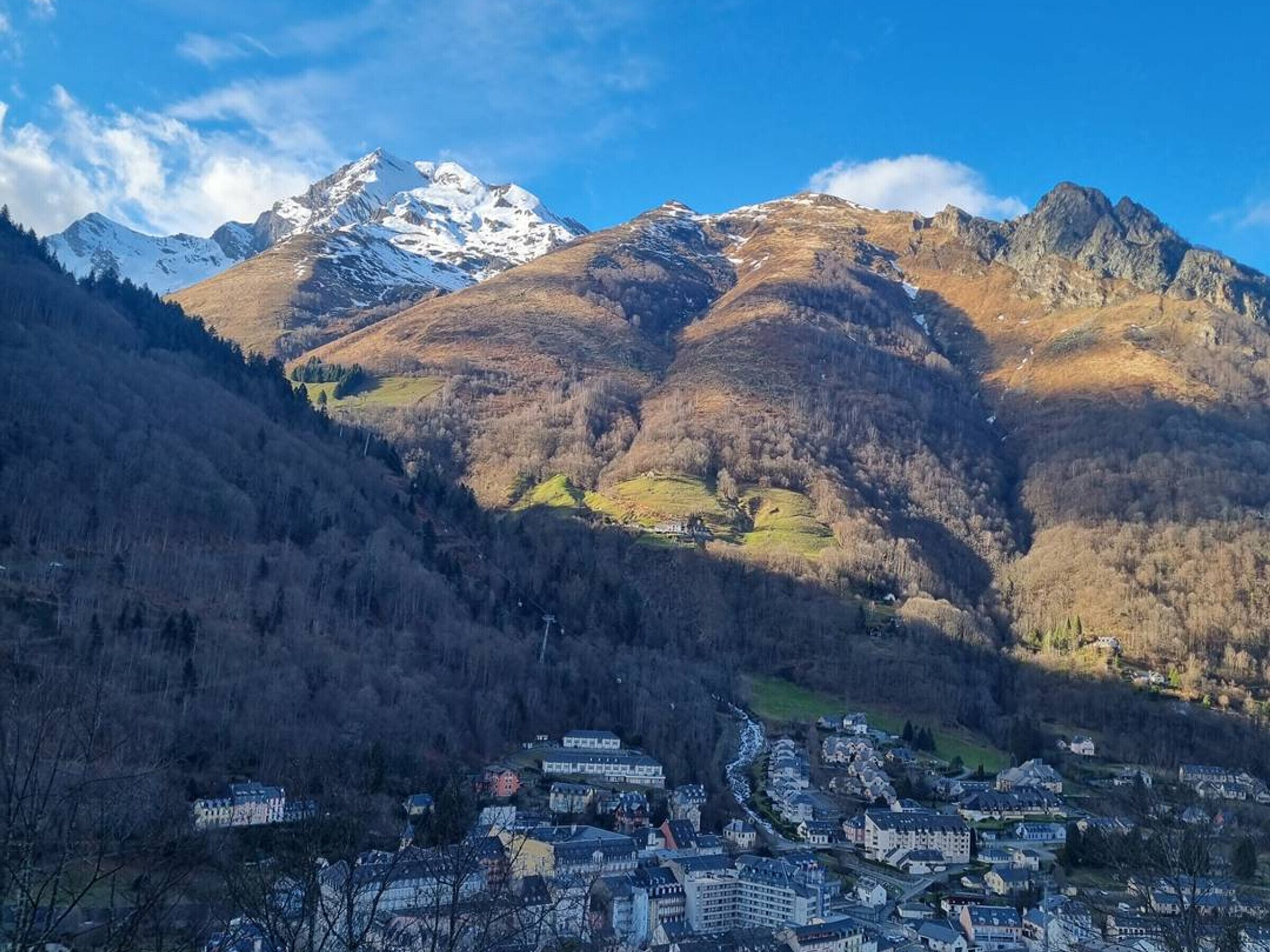 A town nestled in a valley with a backdrop of snow-capped mountains.
