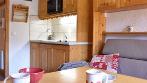 Una cocina acogedora con armarios de madera, un microondas y una tetera sobre la encimera.