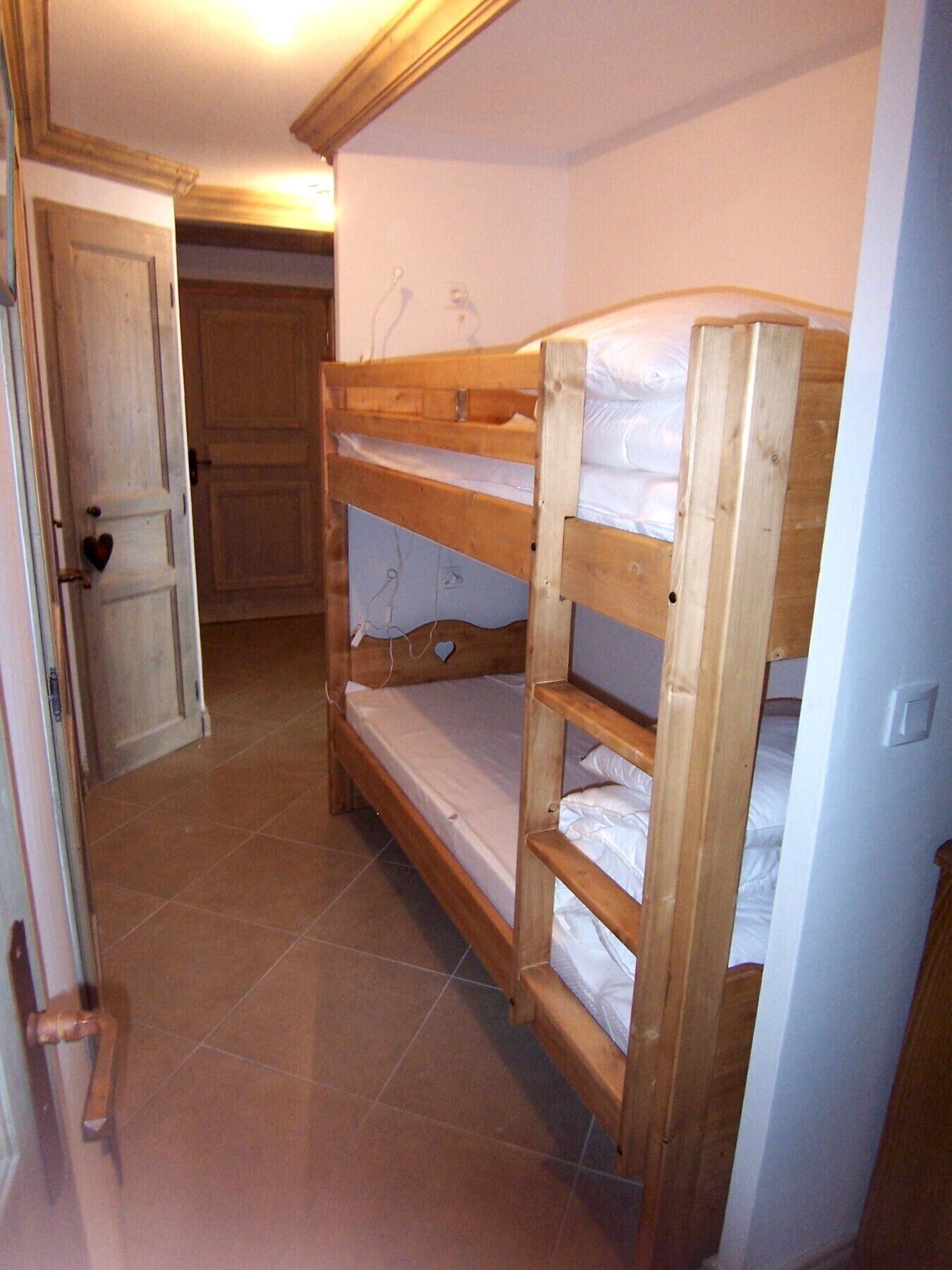 Ein Stockbett in einem Zimmer mit gefliestem Boden und einer Tür, verziert mit einem Herz.