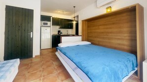 A compact room with a bed, a kitchenette, and a wooden headboard. - Apartment Studio located 50m from the beach of Canyelles Petites, Roses (Rosas / Roses)