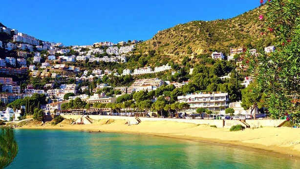 A coastal town with buildings on a hillside, a beach, and clear blue water. - Apartment Studio located 50m from the beach of Canyelles Petites, Roses (Rosas / Roses)