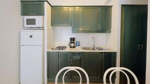 A compact kitchen with a microwave, stove, sink, and two white chairs. - Apartment Studio located 50m from the beach of Canyelles Petites, Roses (Rosas / Roses)