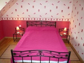 A room with a bed, two bedside tables, and a patterned wall.