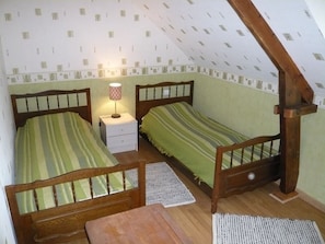 A room with two single beds, a nightstand with a lamp, a wooden chair, and a small table. - House in Réville for 6 pers, fireplace, garden, WIFI (Reville)