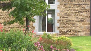 A stone building with a window and a tree in the foreground. - Charming house 3 bdrms., garden, 6 pers. (Le Grand-Celland)