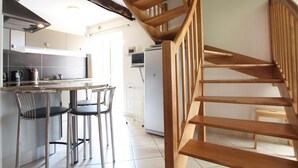 A modern kitchen with a wooden staircase leading to an upper floor. - Charming house 3 bdrms., garden, 6 pers. (Le Grand-Celland)