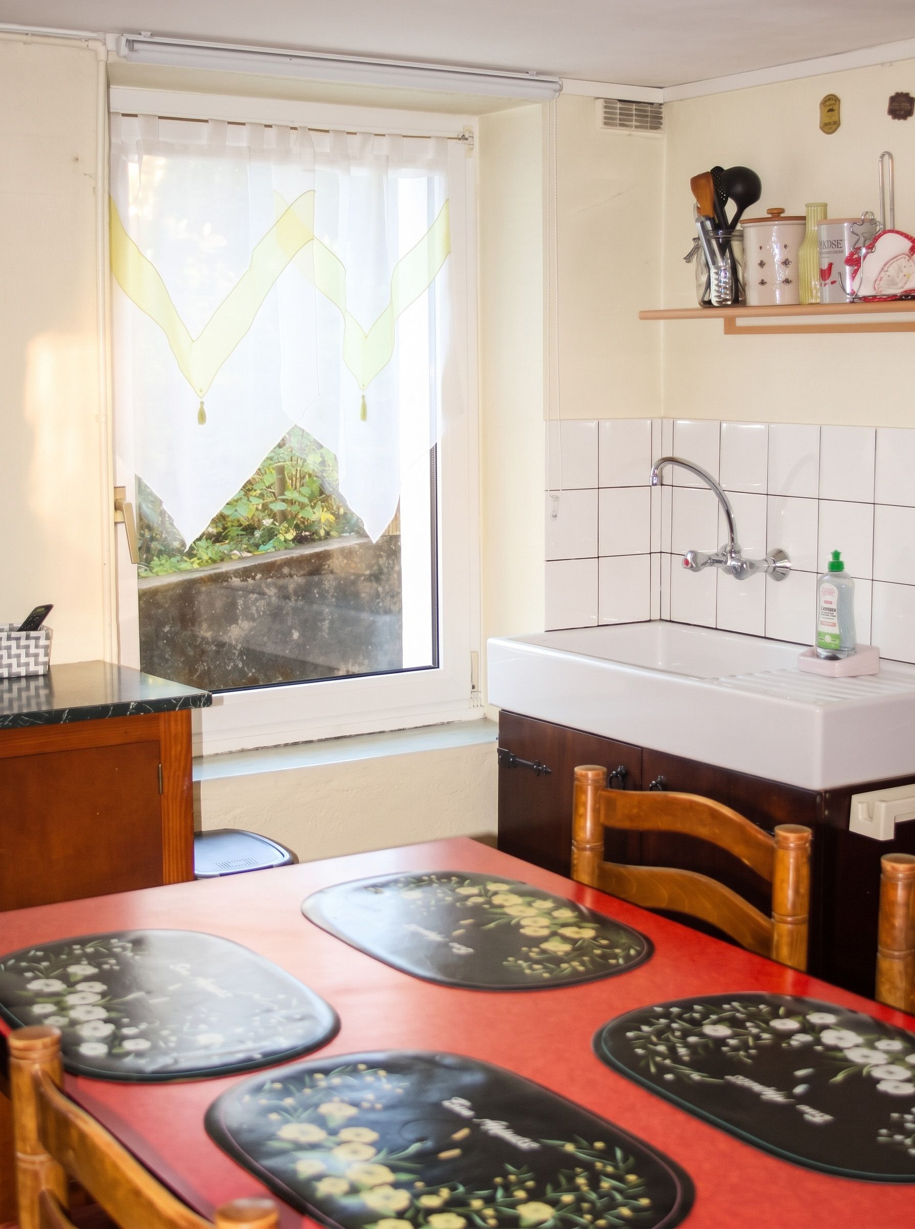 A small kitchen with a window, a sink, and a dining table with placemats.