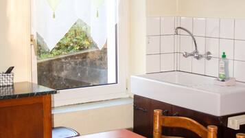 A small kitchen with a window, a sink, and a dining table with placemats.
