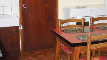Une cuisine de taille réduite avec une porte en bois, un poêle blanc et une table à manger avec des chaises.