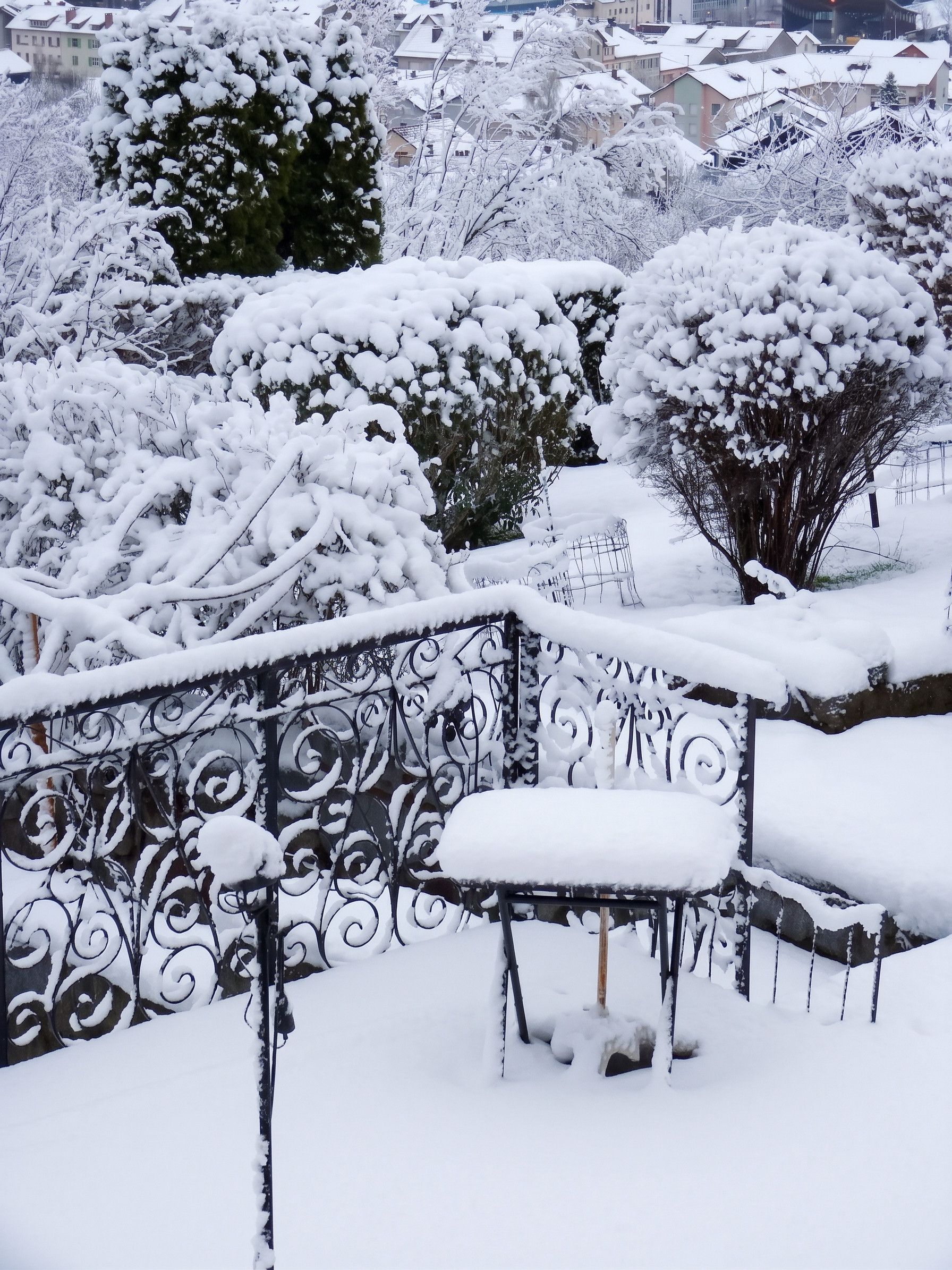 A snow-covered outdoor area with a metal fence and a bench.