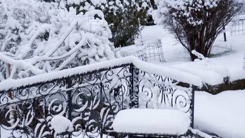 A snow-covered outdoor area with a metal fence and a bench.