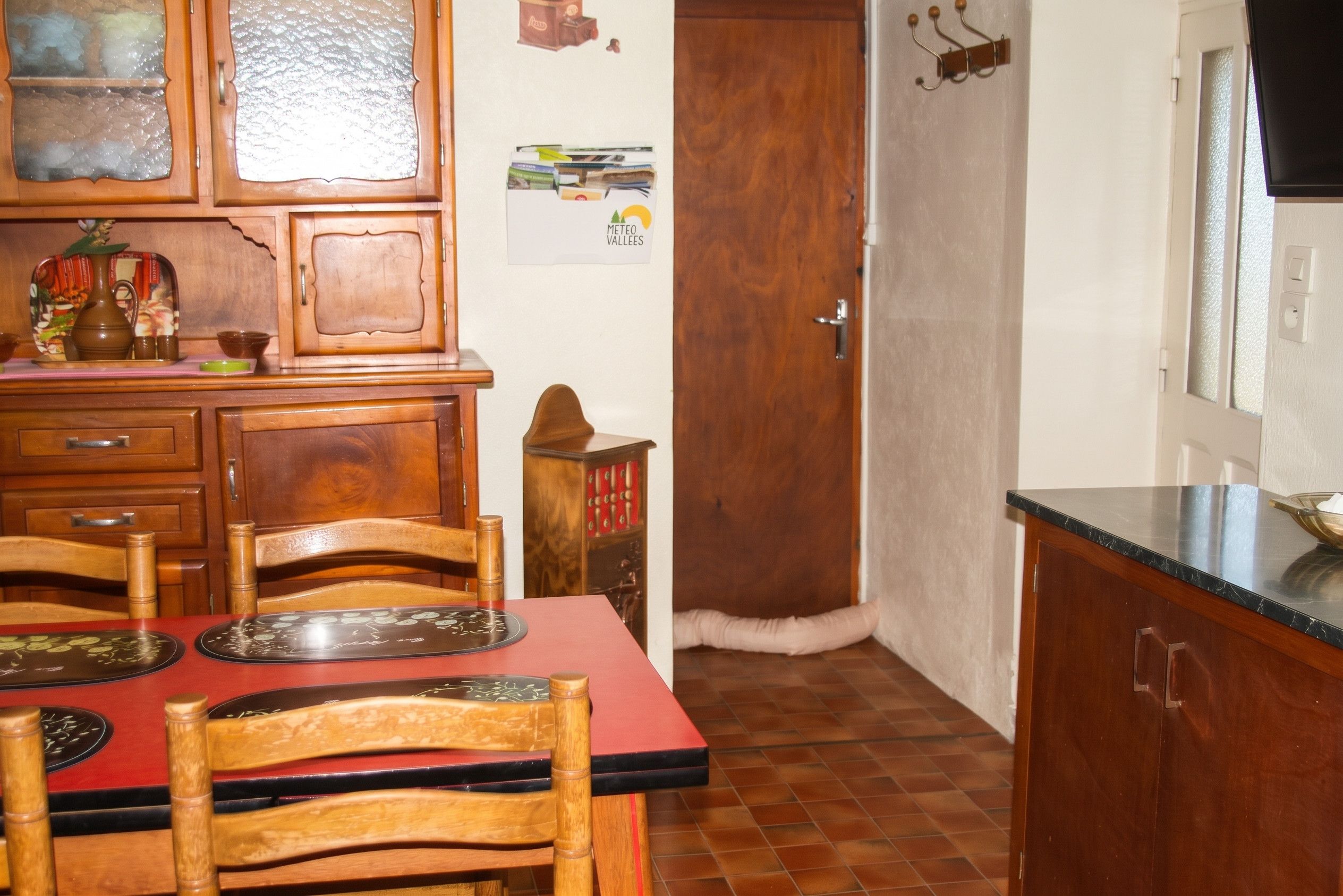 A kitchen with wooden cabinets, a dining table with chairs, and a refrigerator.