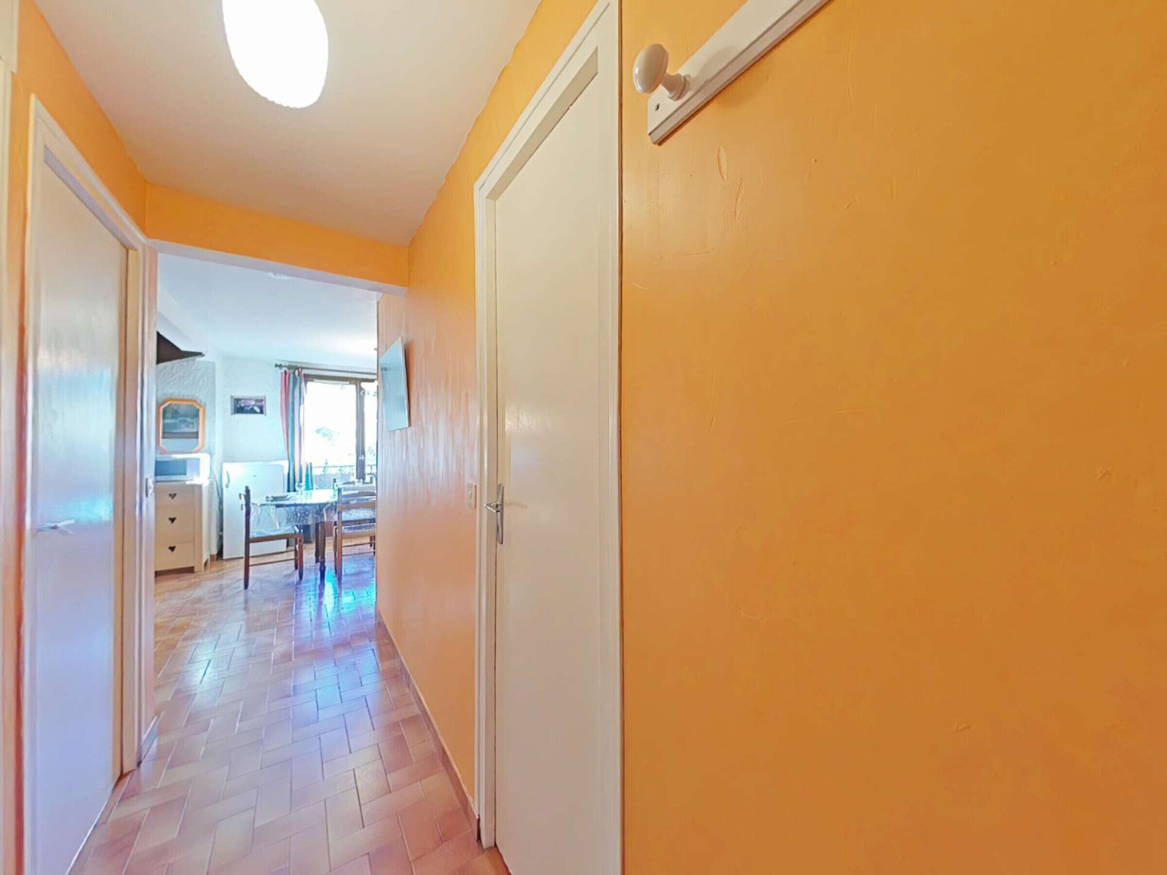 A hallway with wooden flooring leading to a dining area with a table and chairs.