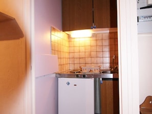 A compact kitchen with a white refrigerator, a small sink, and wooden cabinets. - Cozy studio for 2, near ski lifts, Vieil Alpe (Huez)