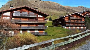 Eine Holzhütte mit mehreren Balkonen vor einer Bergkulisse.