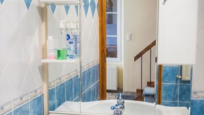 A bathroom with a white sink, blue-tiled walls, and a mirror above the sink. - Homerez - House in Chirens (Chirens)