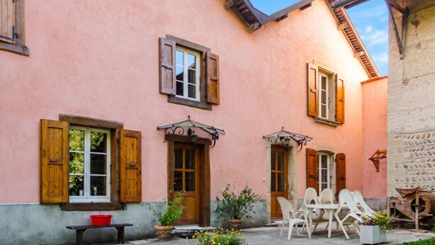 A pink building with wooden shutters, a bench, and outdoor seating. - Homerez - House in Chirens (Chirens)