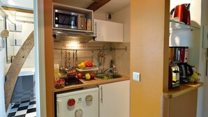 A compact kitchen with a microwave, sink, and a small refrigerator. - C3DD Strolling (París)