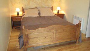 A single bed with a wooden frame and headboard, flanked by two bedside tables with lamps. - Countryside house with pool and spa in Normandy (Savigny (Manche))