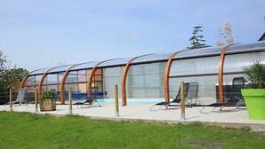 A covered outdoor area with lounge chairs and a pool. - Countryside house with pool and spa in Normandy (Savigny (Manche))