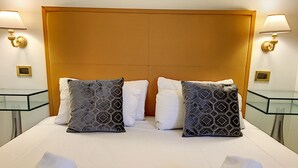 Habitación de hotel con una cama grande, dos almohadas, dos mesitas de noche y dos lámparas.