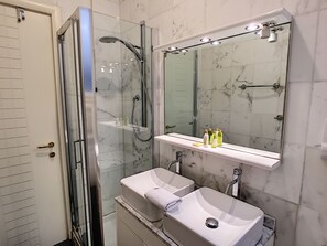 A modern bathroom with a glass-enclosed shower, a white sink, and a large mirror above the vanity. - N&J - PALAIS DE FRANCE - Central - Sea front (Niza)