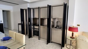 Una cocina moderna con estufa, horno y pileta integrados, y un comedor con mesa y sillas de vidrio.
